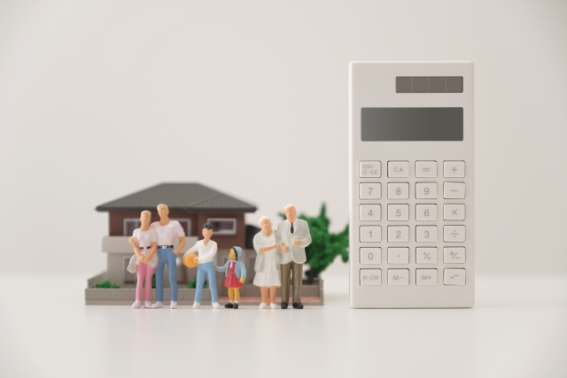 二世帯住宅の費用をイメージした住宅模型と家族と電卓