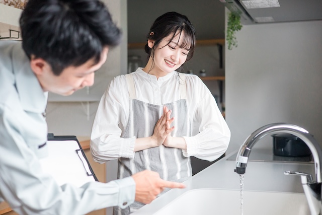 注文住宅のキッチン設備を確認する女性と説明するスタッフ